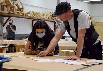 Ausbilder und Auszubildende mit Coronaschutz bei der Unterweisung